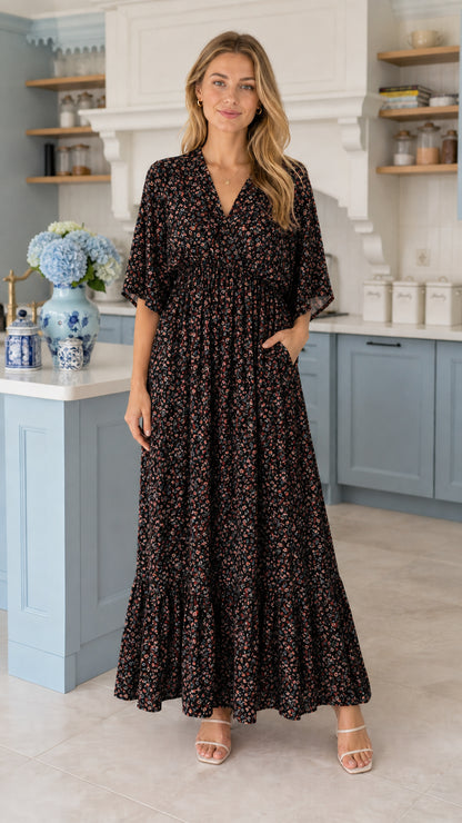 Front view of model wearing black ditsy floral tiered maxi dress with pockets