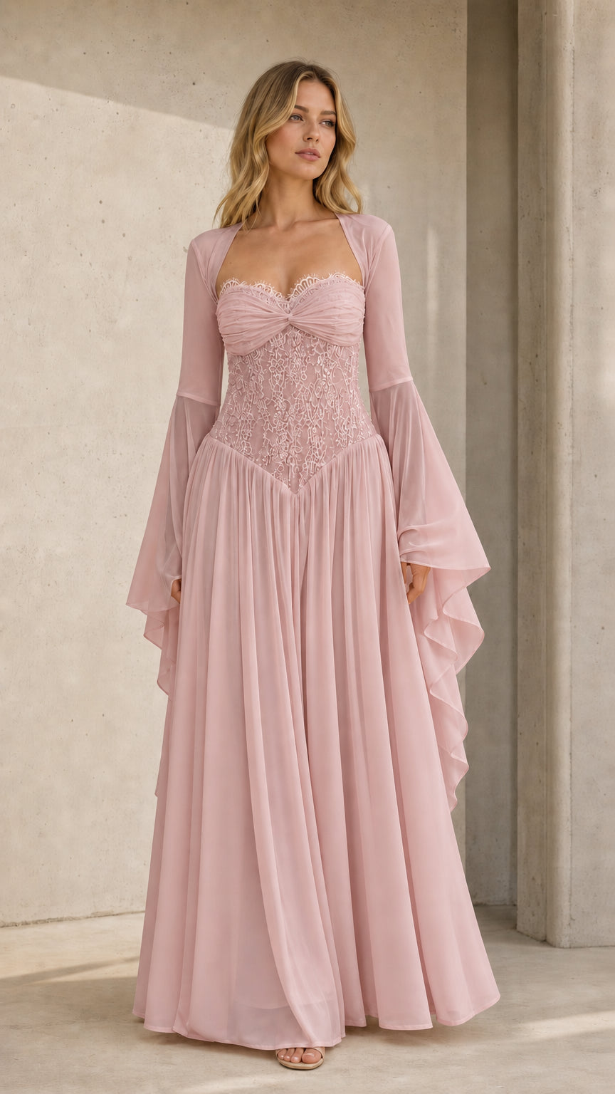 Front view of model wearing dusty pink lace corset evening gown with flared sleeves