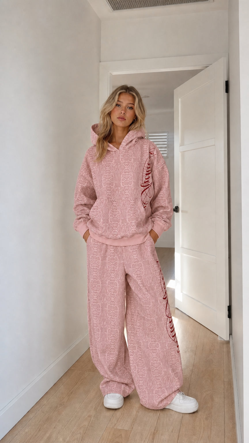 Model wearing pink embossed monogram hoodie and wide-leg tracksuit set
