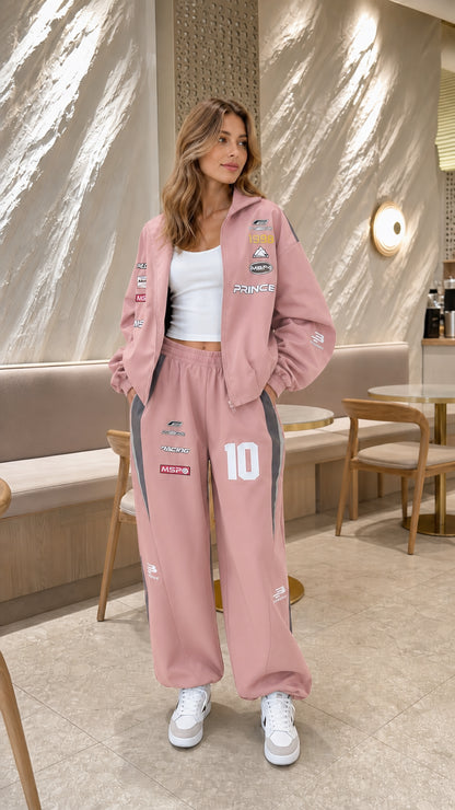 Model wearing dusty pink graphic racing tracksuit set with white sneakers