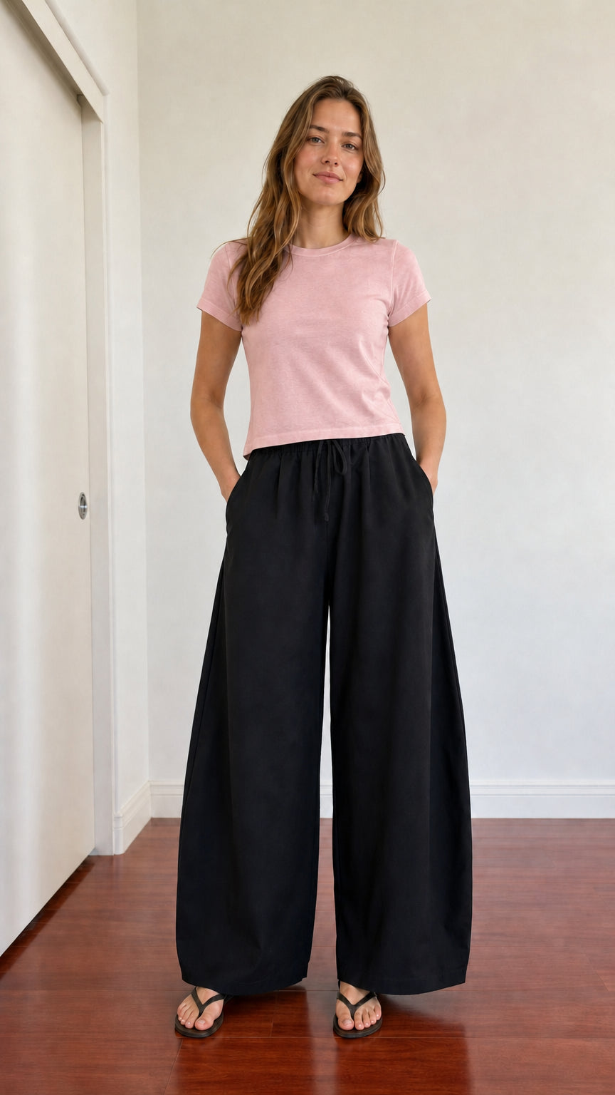Full-body look of model in black wide leg pants paired with a blush pink tee