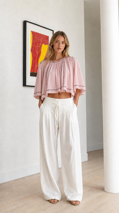 Front view of blush pink embroidered cropped blouse paired with white trousers
