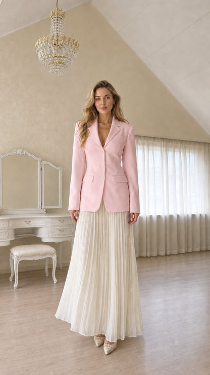 Full length view of a woman wearing a pink tailored blazer and pleated skirt