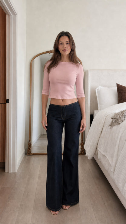 Front view of woman wearing pink ribbed cropped top and dark denim jeans