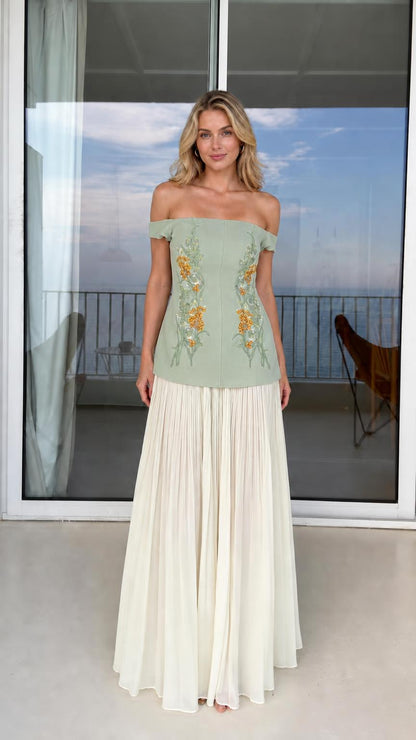 Model wearing sage green off-shoulder floral embroidered top with white pleated skirt