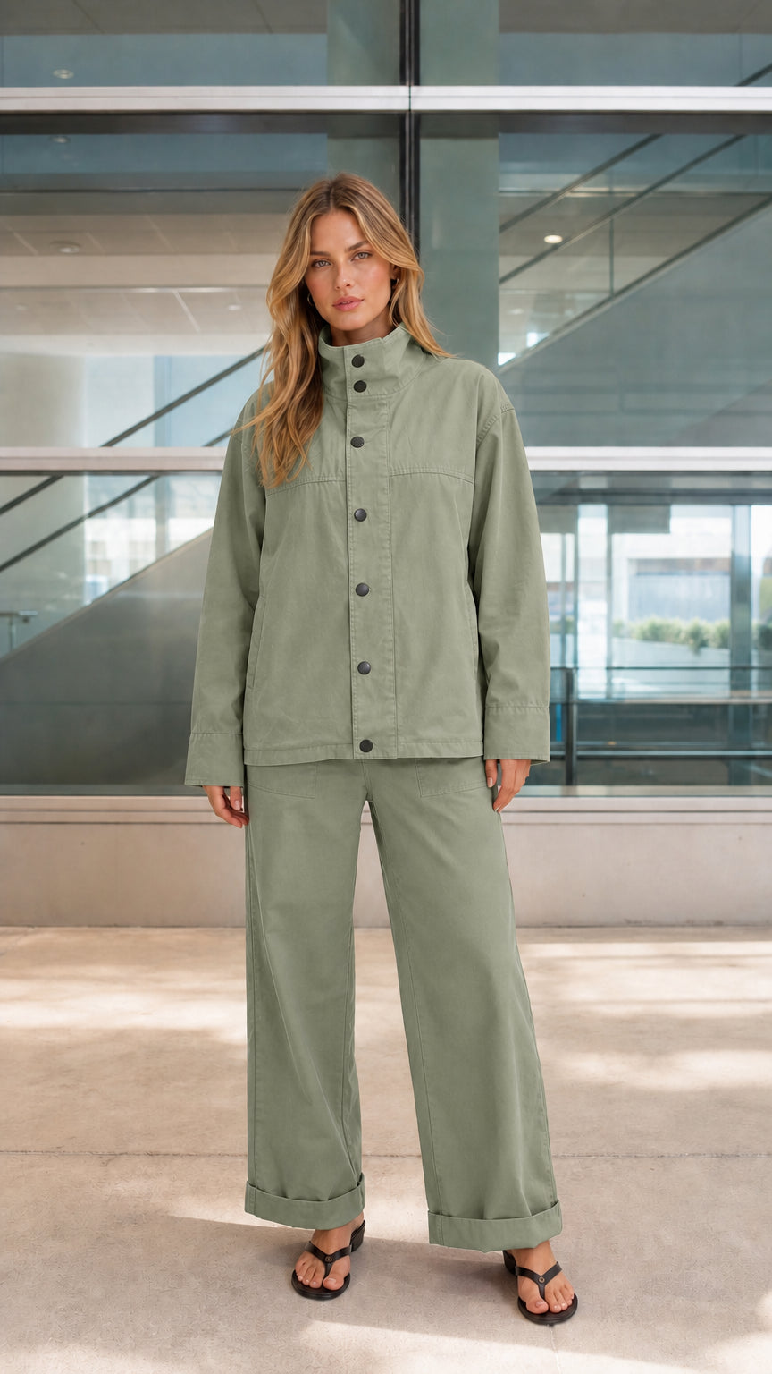 Woman wearing sage green two-piece snap-front jacket and pants set