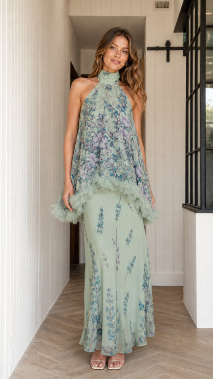 Model wearing sage green floral halter maxi dress with ruffle overlay