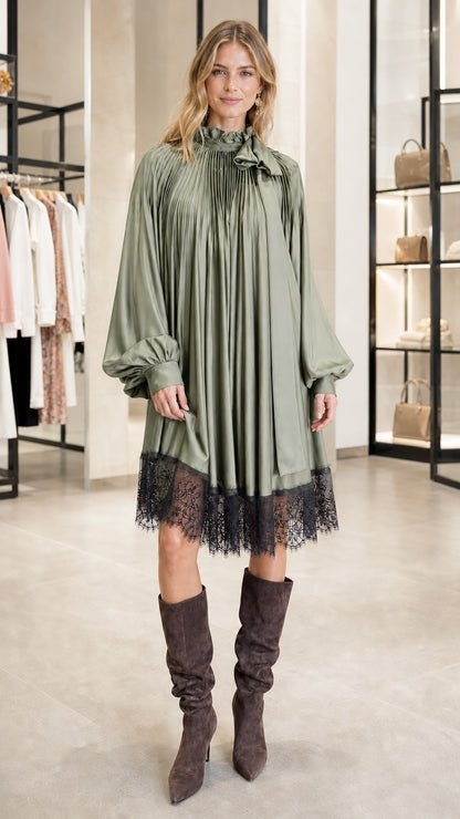 Model wearing sage green pleated satin dress with lace hem