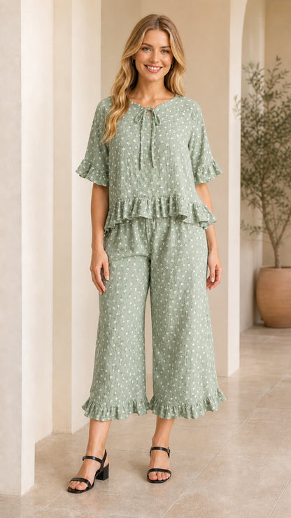 Front view of model wearing sage green floral ruffle top and cropped pants set