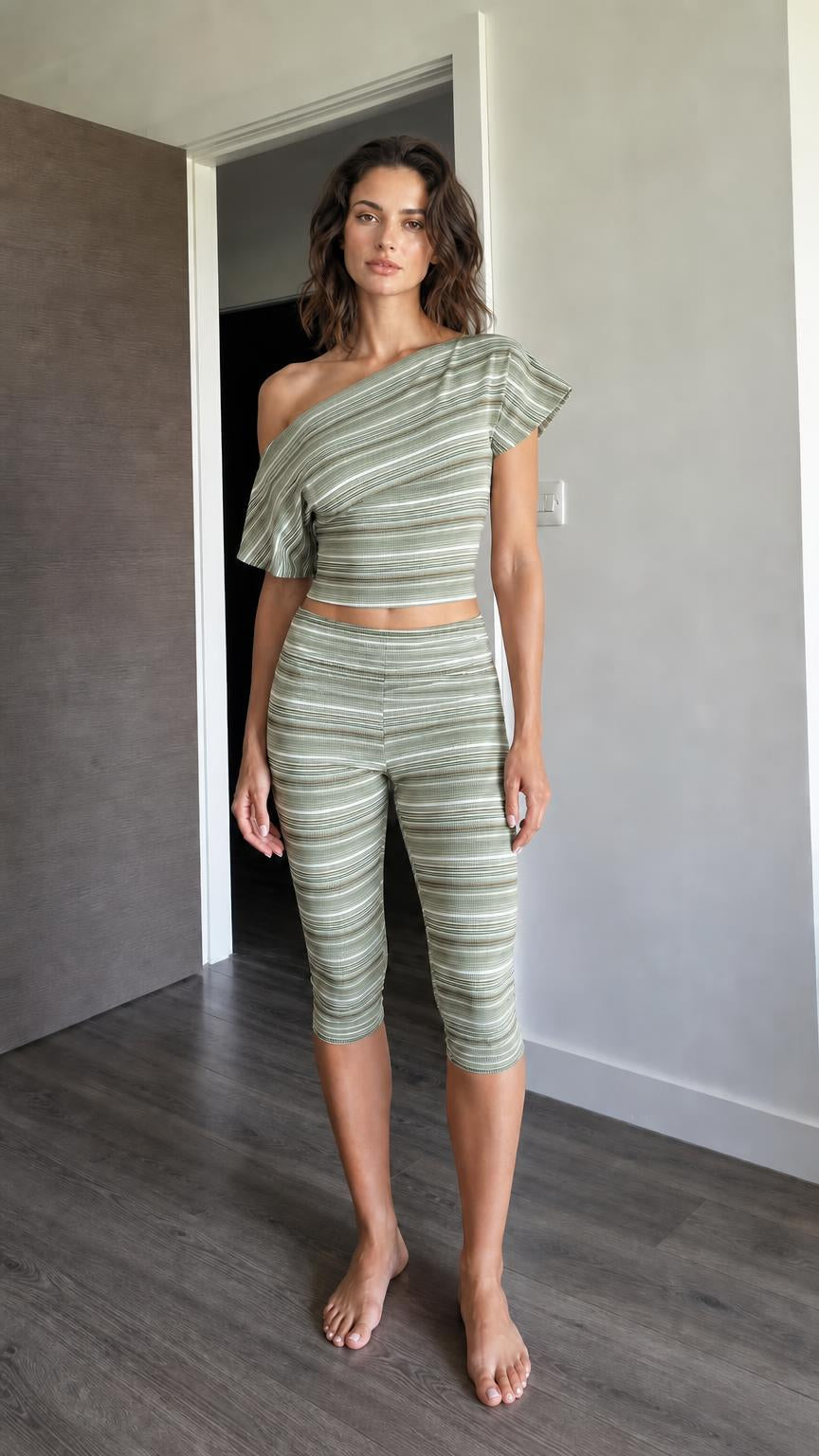 Woman wearing sage green striped one-shoulder crop top and capri leggings set