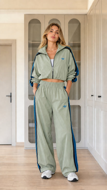Model wearing sage green two-piece cropped tracksuit with blue side stripe detail