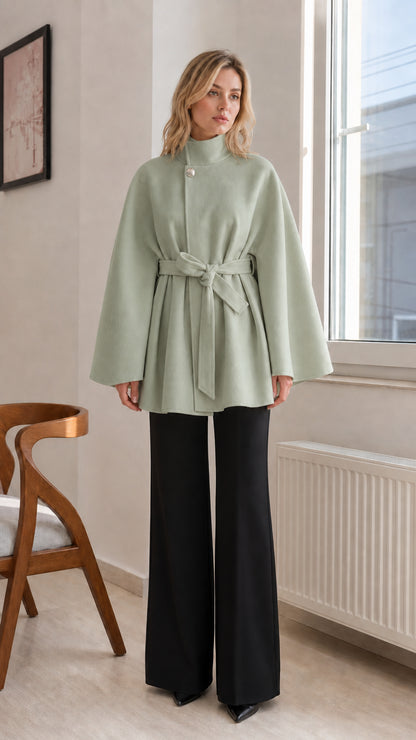 Sage green high-neck belted cape coat paired with tailored black pants