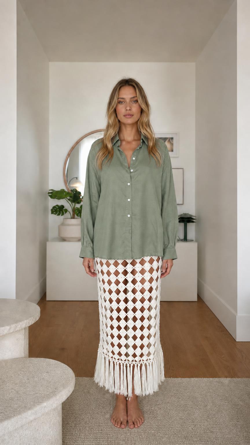 Model wearing sage green long sleeve button-down shirt and patterned fringe skirt