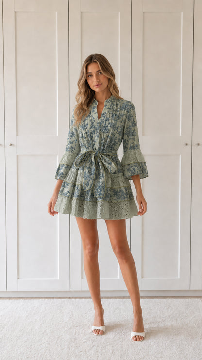 Front view of woman wearing sage green floral print ruffle mini dress