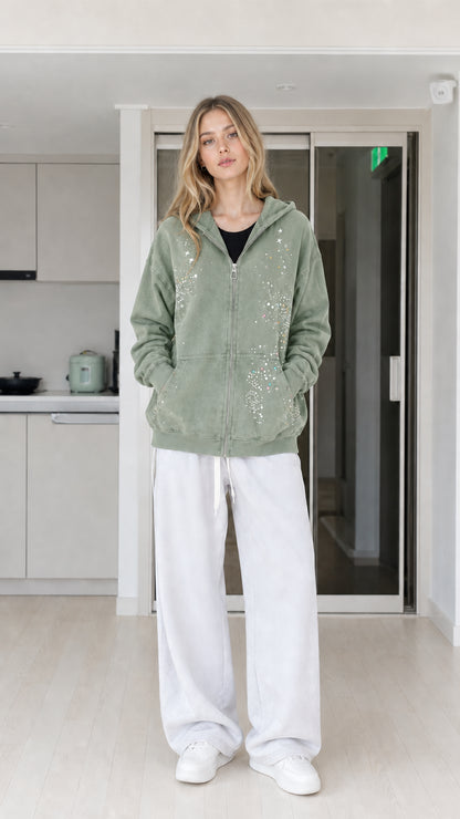 Front view of woman wearing sage green rhinestone star zip-up hoodie