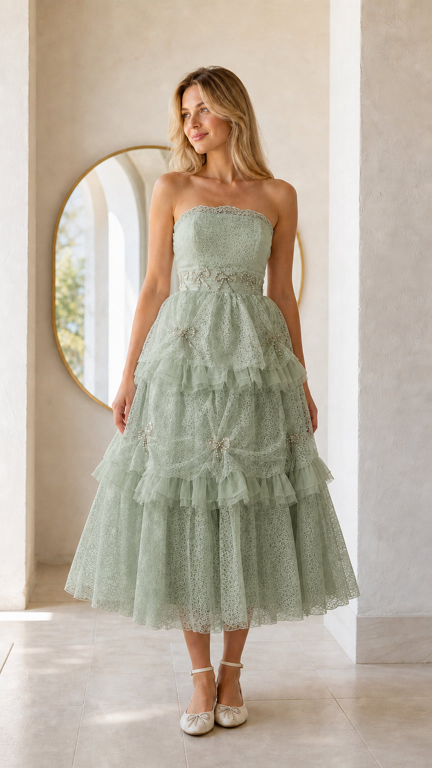 Front full view of woman wearing sage green strapless tiered midi dress
