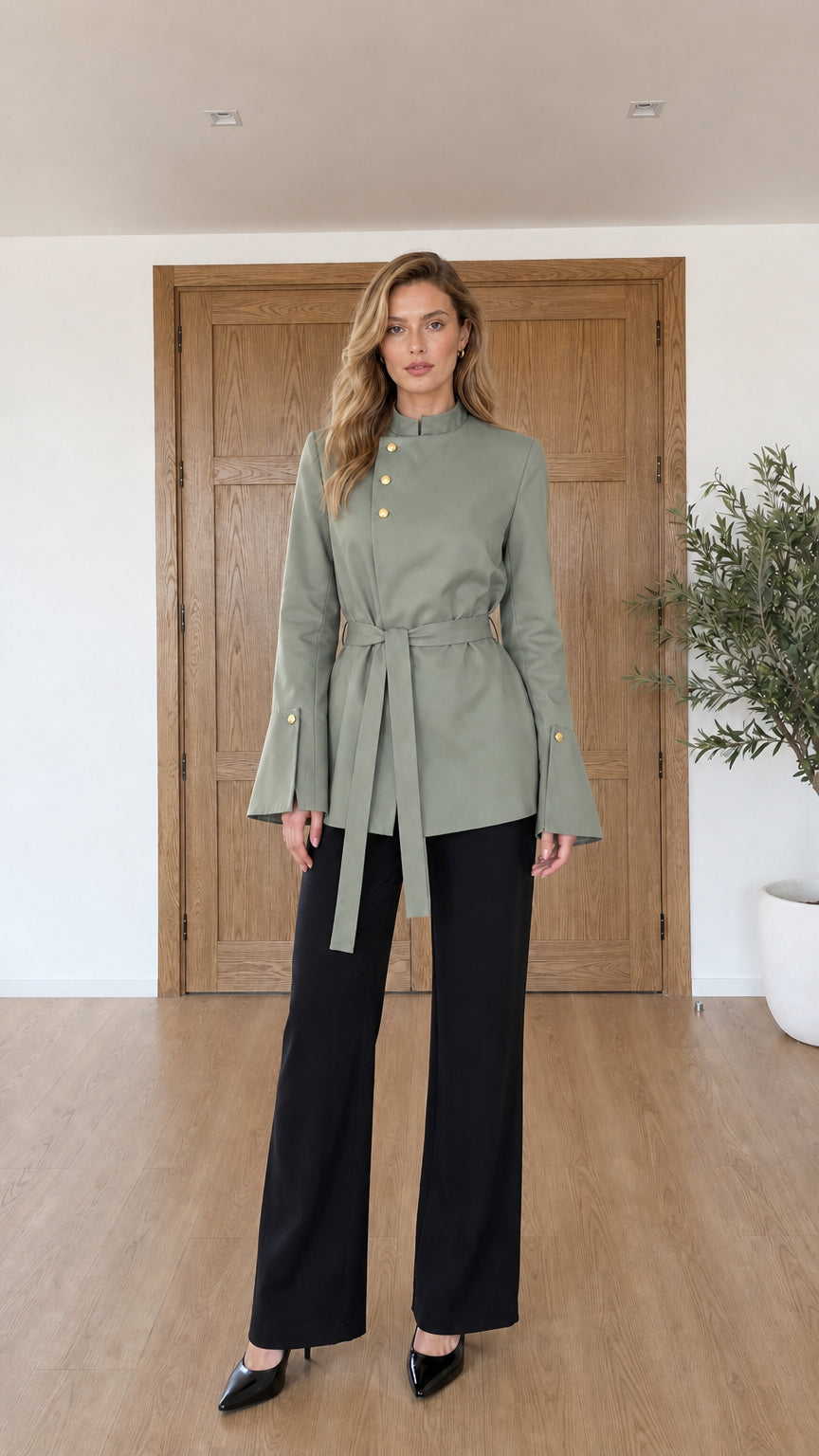 Model wearing sage green asymmetrical belted tunic jacket