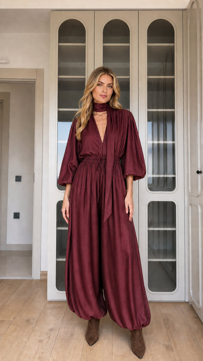 Front view of woman wearing burgundy wine draped balloon sleeve jumpsuit
