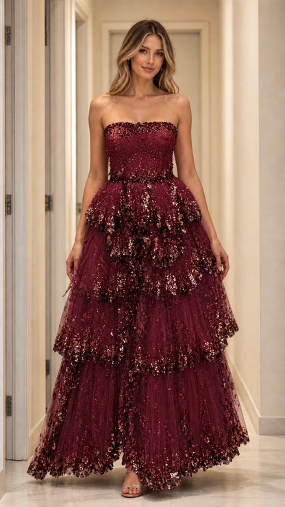 Model wearing burgundy strapless tiered sequin gown