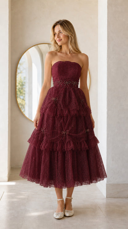 Front full view of woman wearing burgundy strapless tiered midi dress