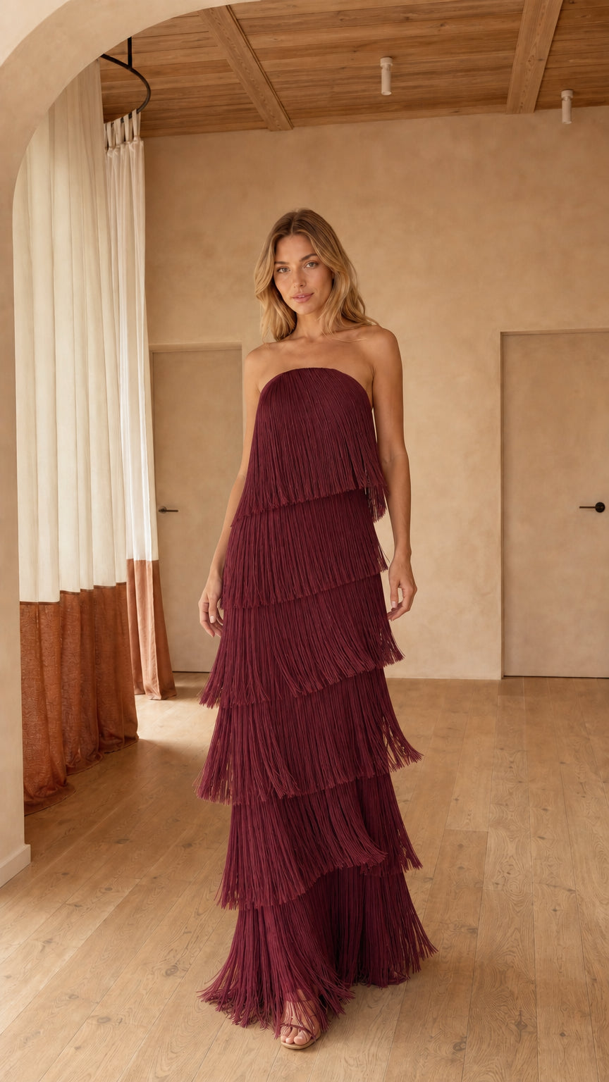 Front full-length view of strapless burgundy tiered fringe maxi dress