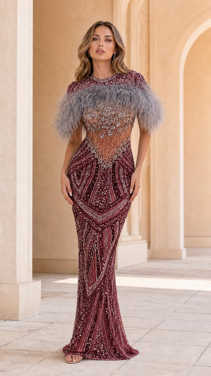 Model wearing Burgundy wine sequin gown with feather cape collar