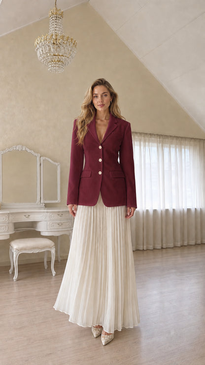 Full length view of a woman wearing a burgundy tailored blazer and pleated skirt