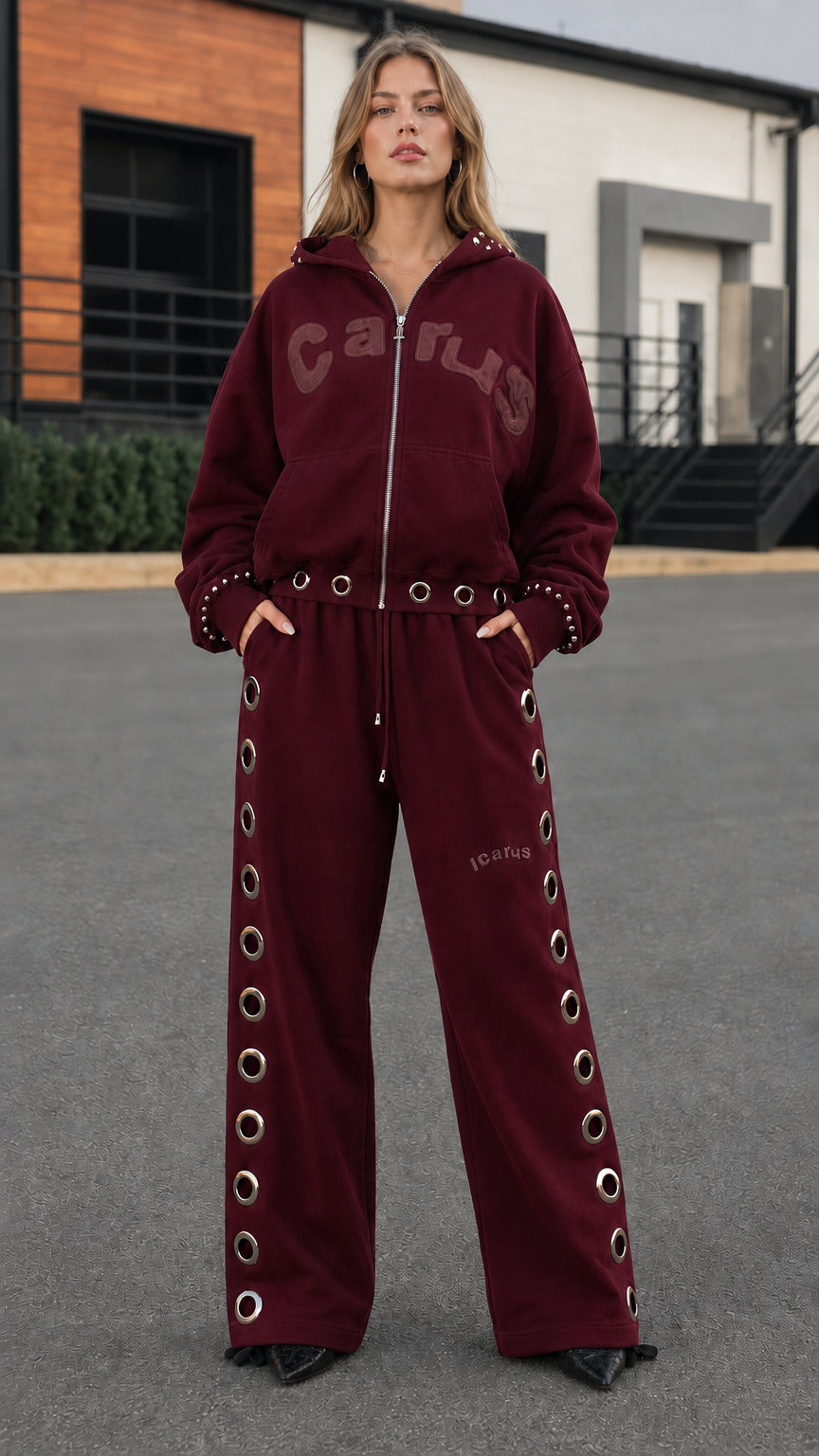 Full front view of model wearing burgundy wine grommet tracksuit set