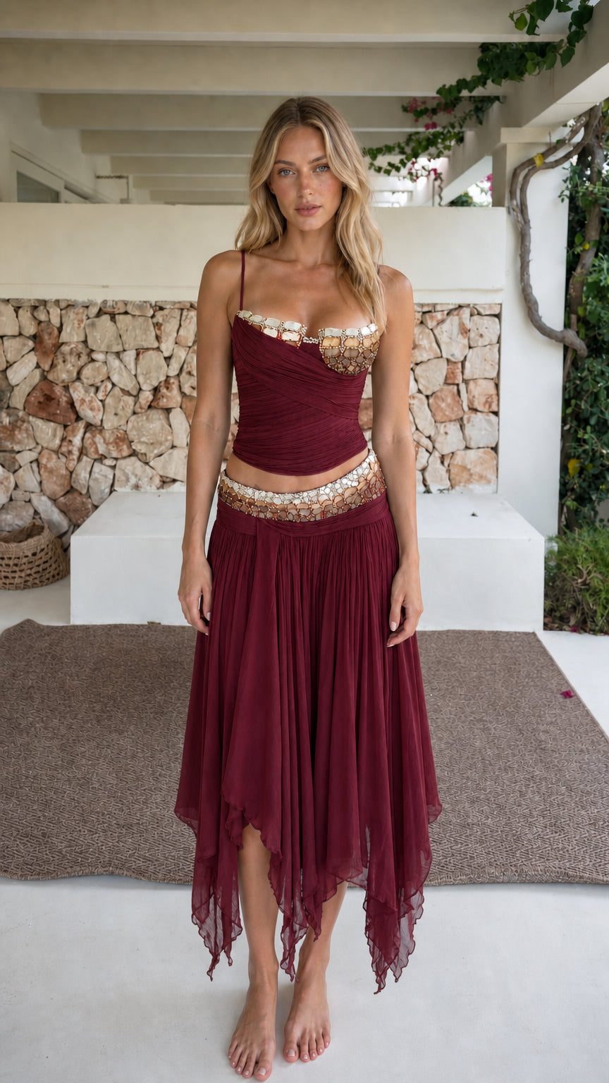 Model wearing burgundy two-piece beaded crop top and skirt set