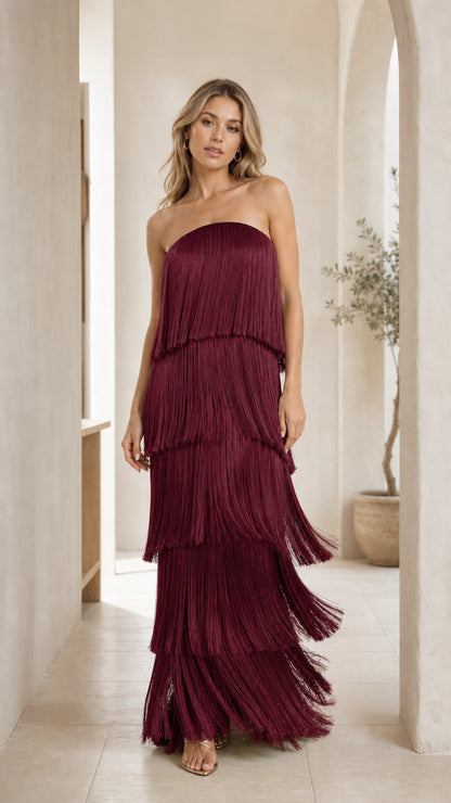 Front view of woman wearing burgundy strapless tiered fringe maxi dress