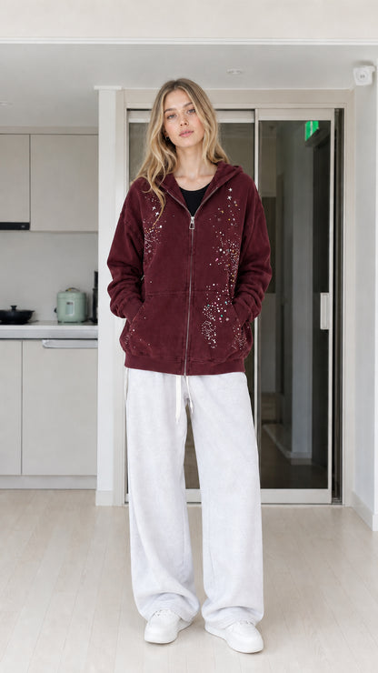 Front view of woman wearing burgundy rhinestone star zip-up hoodie