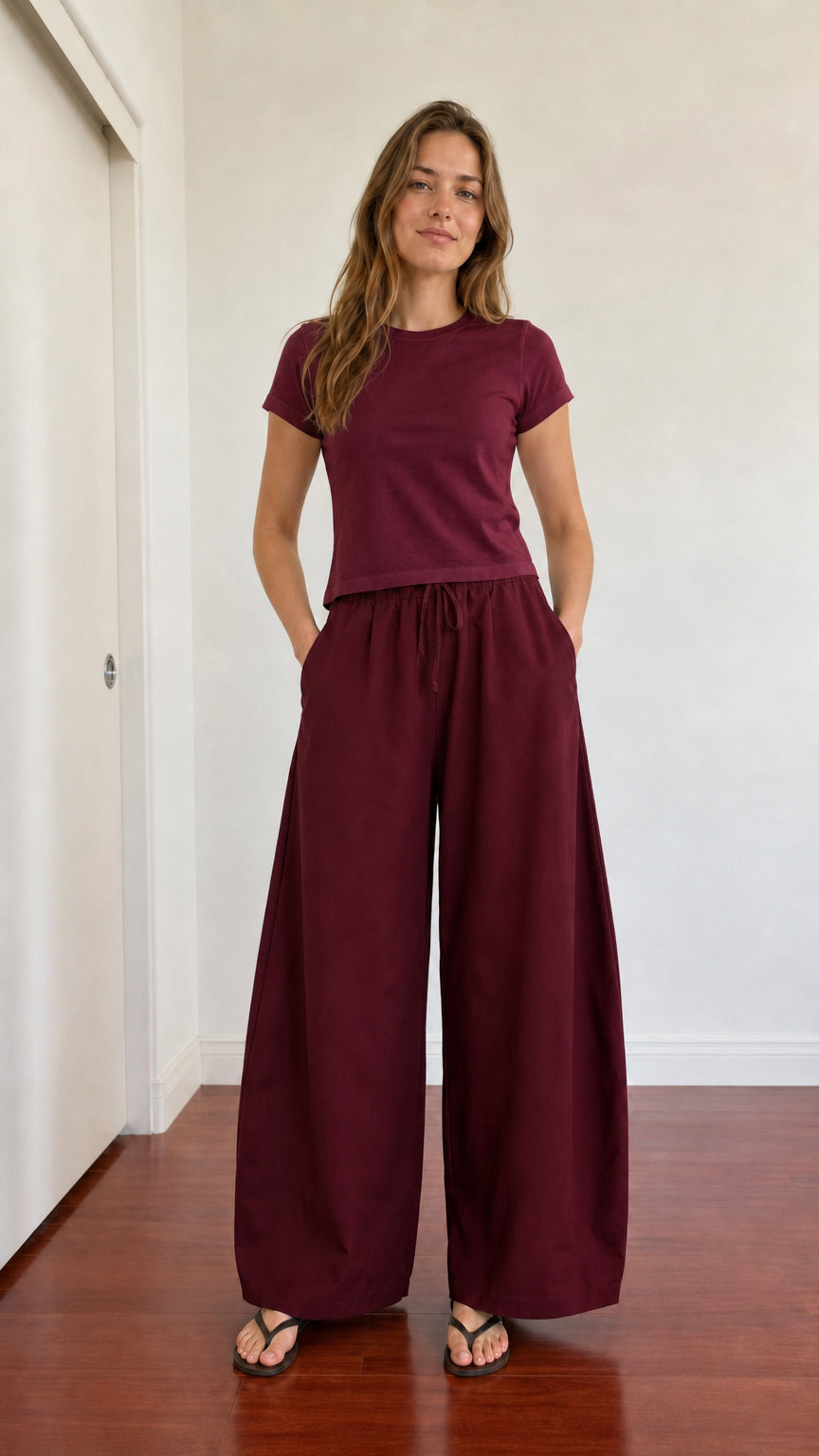 Model in deep burgundy wide leg drawstring trousers and matching maroon top