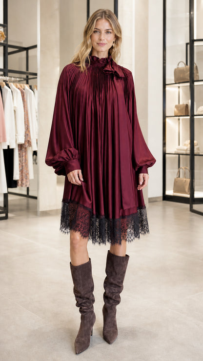 Model wearing burgundy pleated satin dress with lace hem
