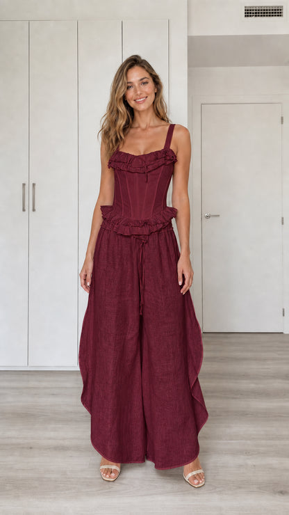 Model wearing burgundy ruffled corset top and wide-leg pants set