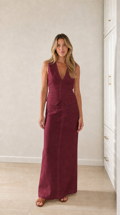 Full-body view of woman wearing burgundy vest and maxi skirt set
