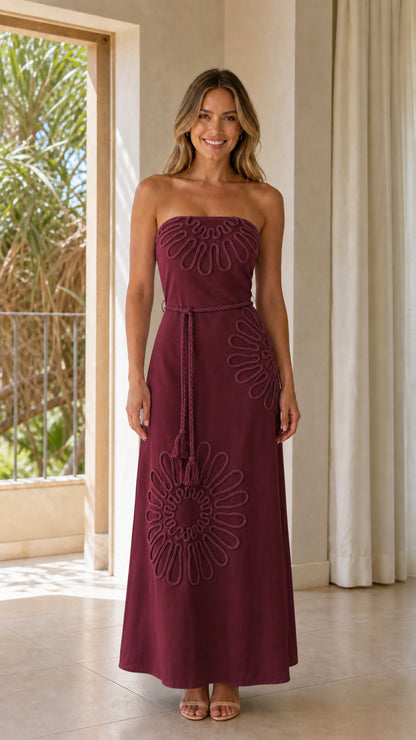 Woman wearing burgundy strapless maxi dress with matching appliques