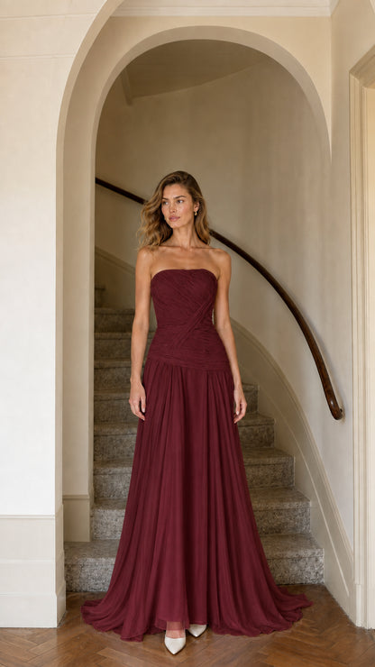Model wearing burgundy red strapless pleated maxi bridesmaid dress