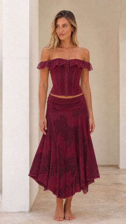 Woman wearing burgundy off-shoulder lace corset top and midi skirt set