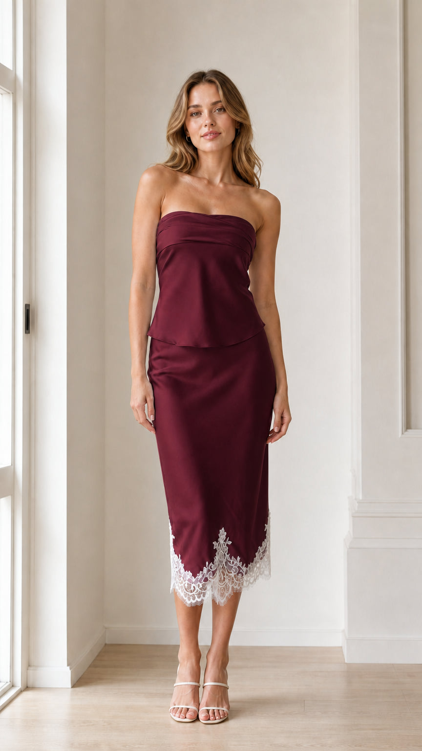 Woman wearing burgundy strapless satin midi dress with white lace hem
