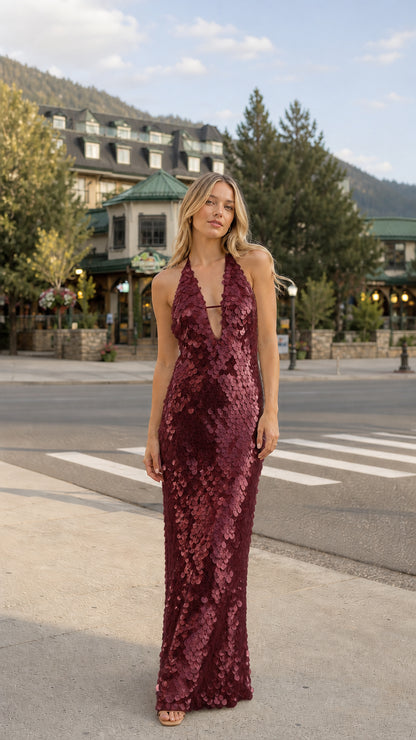 Woman wearing burgundy sequin halter maxi dress