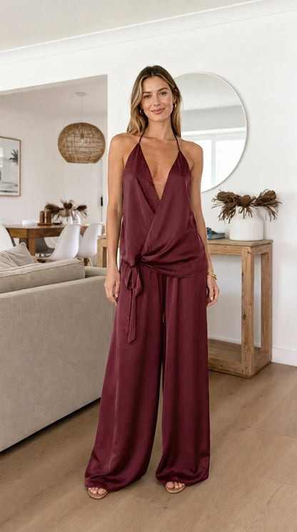 Model wearing burgundy satin halter top and wide leg pants set
