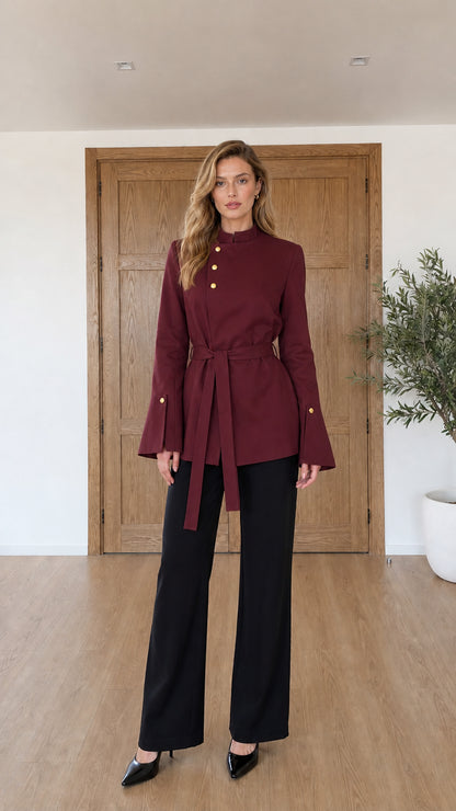 Model wearing burgundy red asymmetrical belted jacket