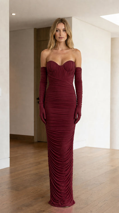 Front view of model wearing burgundy strapless ruched maxi dress and gloves