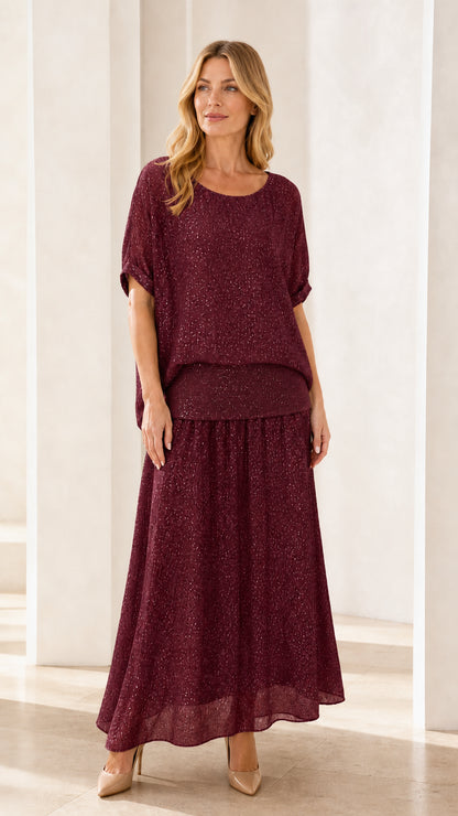 Model wearing burgundy shimmer two-piece maxi skirt set