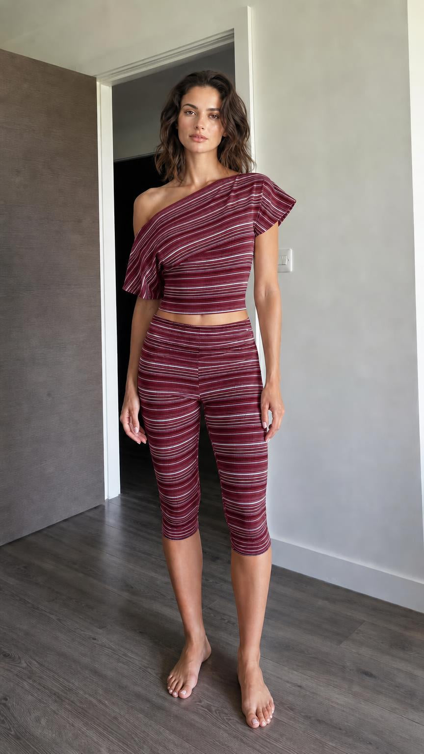 Woman wearing burgundy striped one-shoulder crop top and capri leggings set