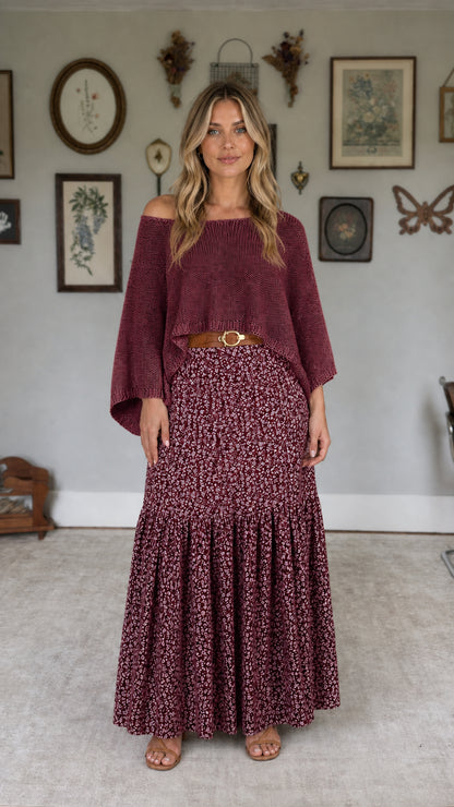 Model wearing burgundy off-the-shoulder knit top and burgundy floral maxi skirt set