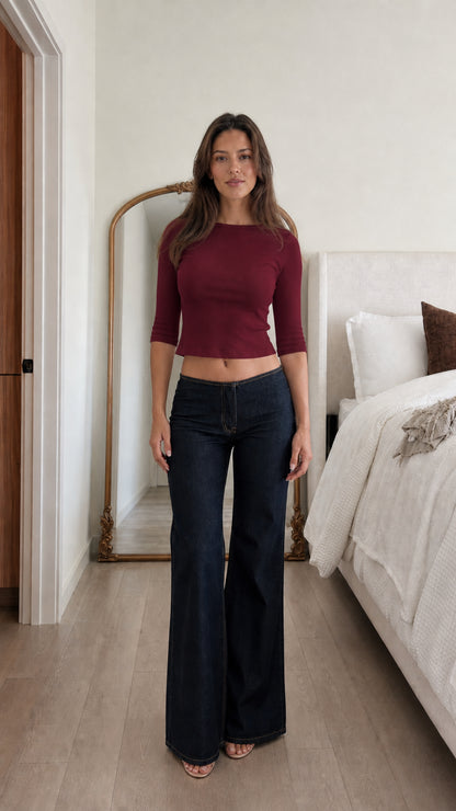 Front view of woman wearing burgundy ribbed cropped top and dark denim jeans