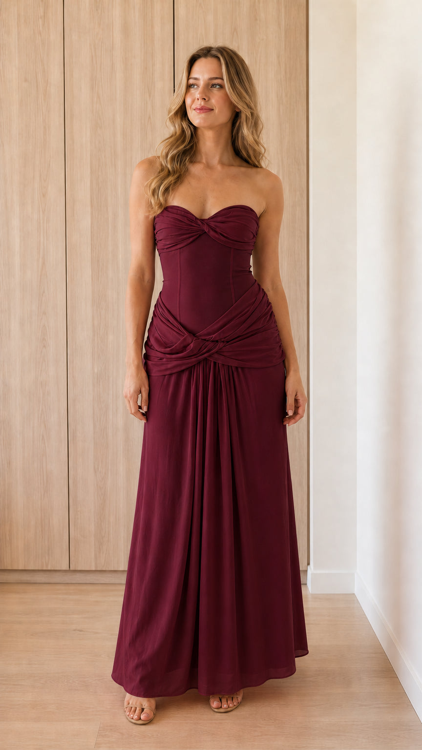 Model wearing burgundy strapless draped corset maxi dress