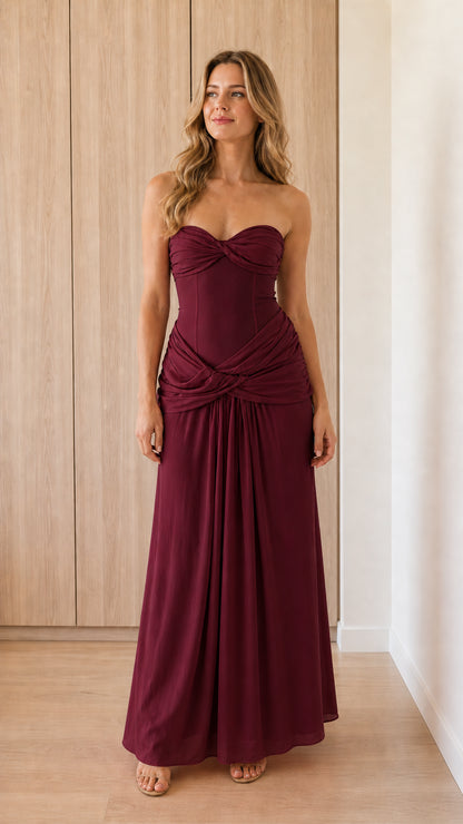 Model wearing burgundy strapless draped corset maxi dress