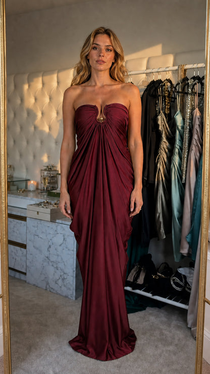 Model wearing burgundy satin strapless draped evening dress
